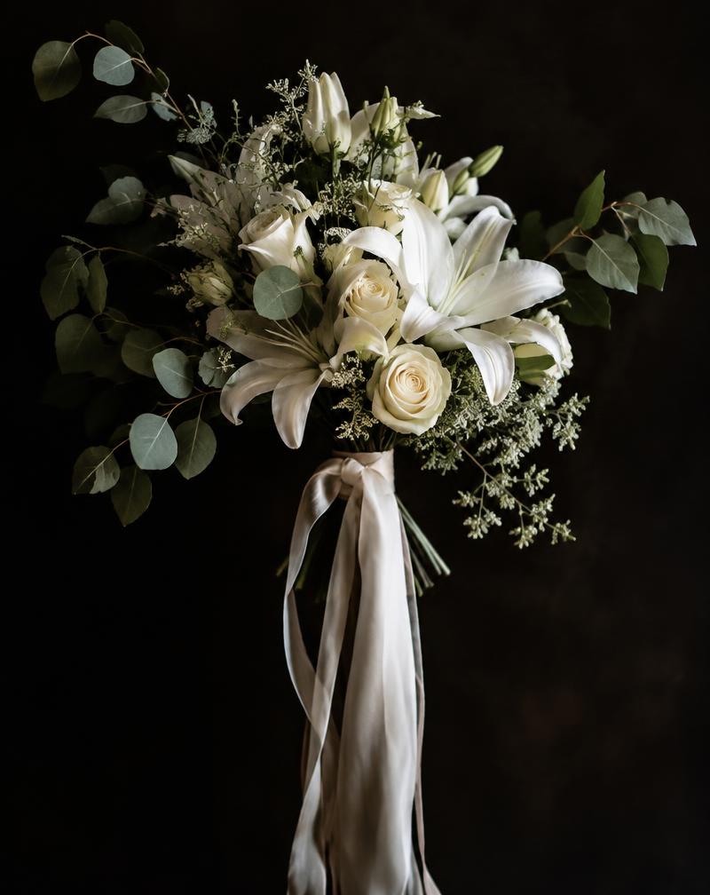 Hand-tied bridal bouquet of white lilies and roses with trailing silk ribbons